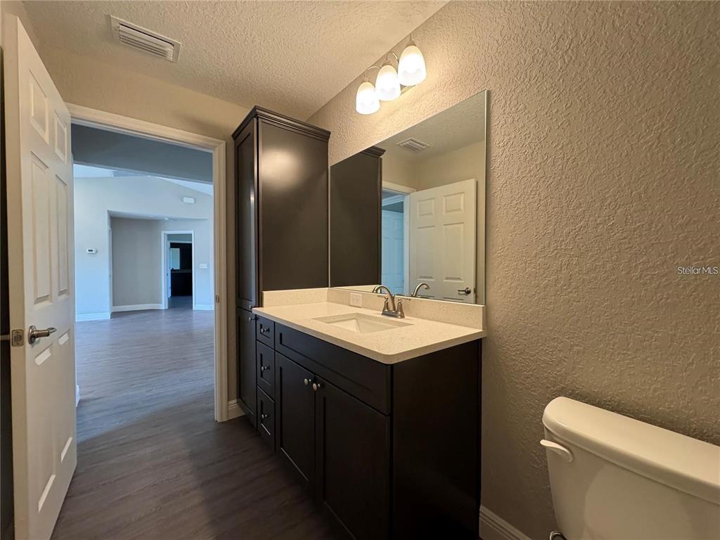 A bathroom features a dark wood vanity with a light countertop and a tall cabinet — 3957 SE 137TH LANE, SUMMERFIELD, FL
