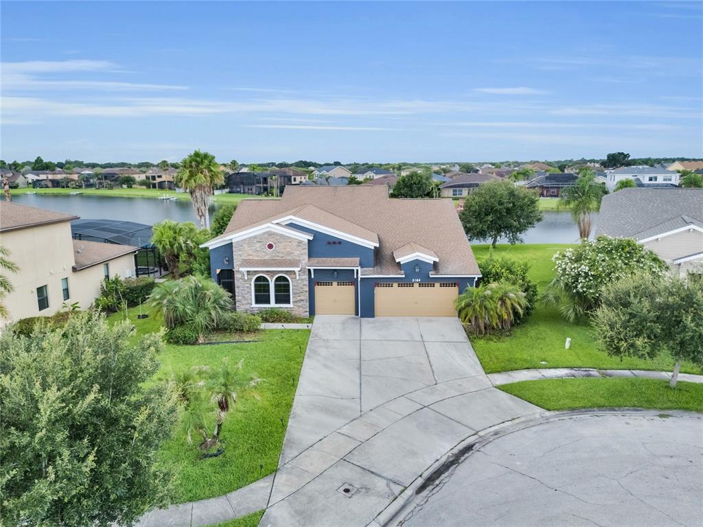 An aerial view shows a blue house with a stone facade and a three-car garage — 3104 BASS BOAT WAY, KISSIMMEE, FL