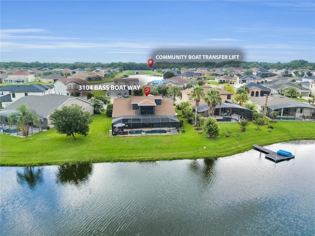 An aerial view shows a house with a pool and screened lanai beside a lake — 3104 BASS BOAT WAY, KISSIMMEE, FL