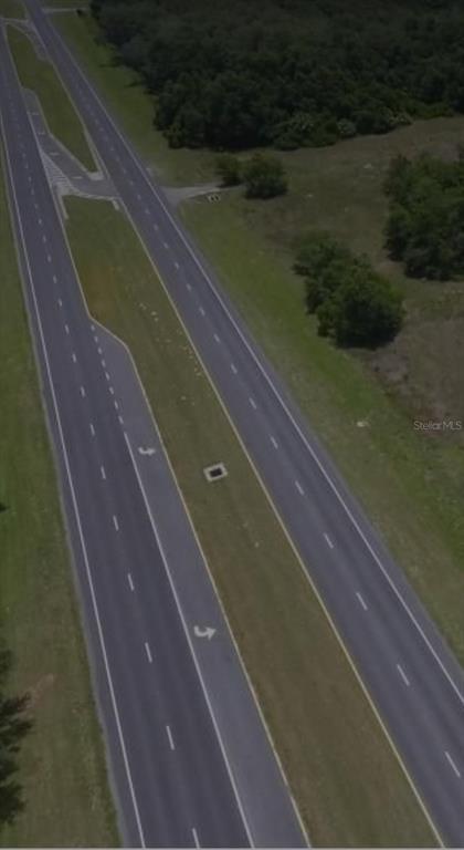 An aerial view shows a multi-lane divided highway with turn lanes and surrounding grassy areas — SE 132ND STREET, SUMMERFIELD, FL
