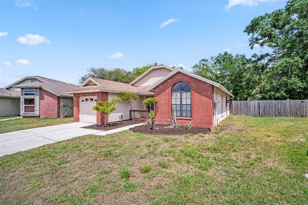 A single-story house with a brick facade, arched window, and attached garage under a blue sky — 5341 SOUTHWICK DRIVE, TAMPA, FL