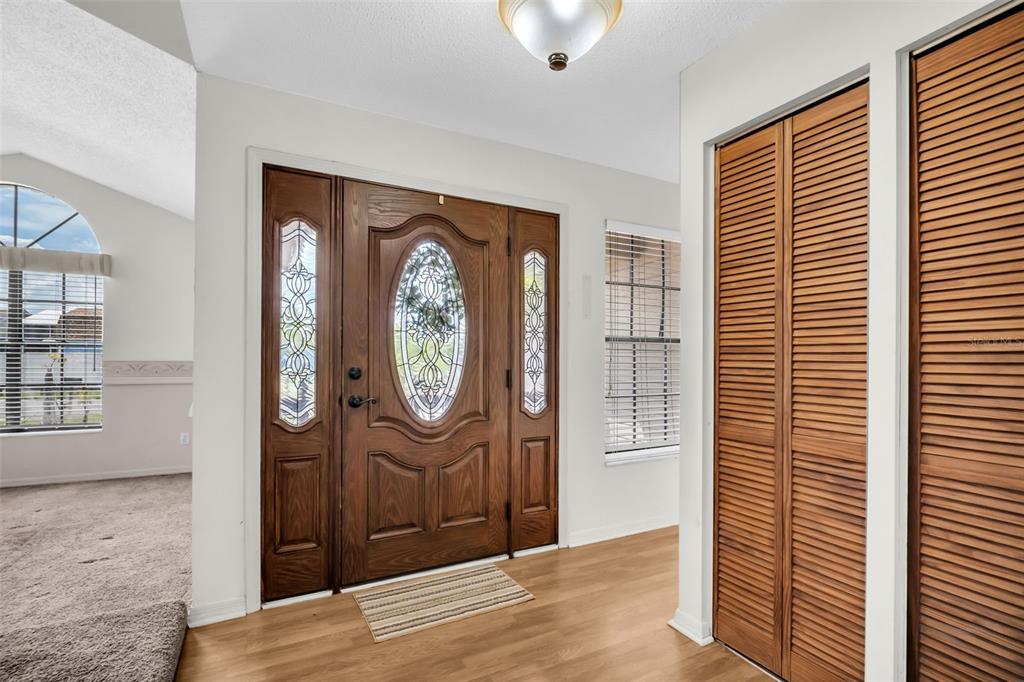 An entryway features a wooden front door with glass inserts, light flooring, and louvered closet doors — 5341 SOUTHWICK DRIVE, TAMPA, FL
