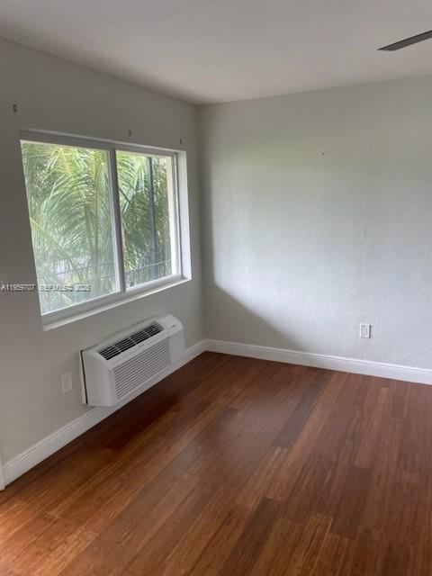A bedroom with hardwood floors, a window, and a wall-mounted air conditioning unit — 2121 Biarritz Dr # 5, Miami Beach FL 33141, MIAMI BEACH, FL