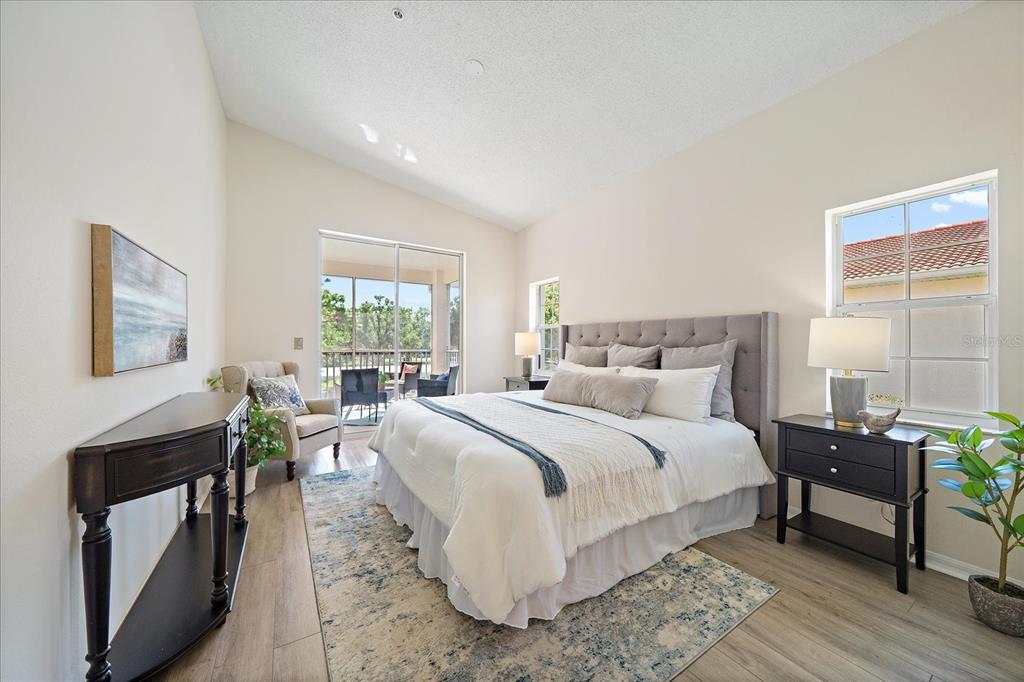 A bedroom features a bed, a console table, a chair, and a sliding glass door — 4256 CENTRAL SARASOTA PARKWAY UNIT 321, SARASOTA, FL
