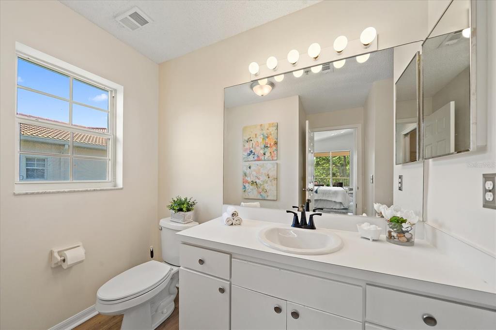 A bathroom features a white vanity, a large mirror, a toilet, and a window — 4256 CENTRAL SARASOTA PARKWAY UNIT 321, SARASOTA, FL