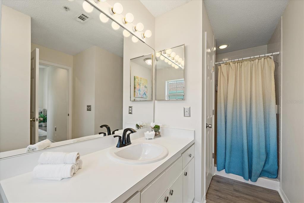 A bathroom features a white vanity with a dark faucet, a large mirror, and a shower — 4256 CENTRAL SARASOTA PARKWAY UNIT 321, SARASOTA, FL