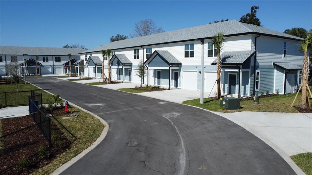 An exterior view of a multi-unit townhouse complex with attached garages and paved driveways — 1111 E CAROLINE STREET, TAVARES, FL