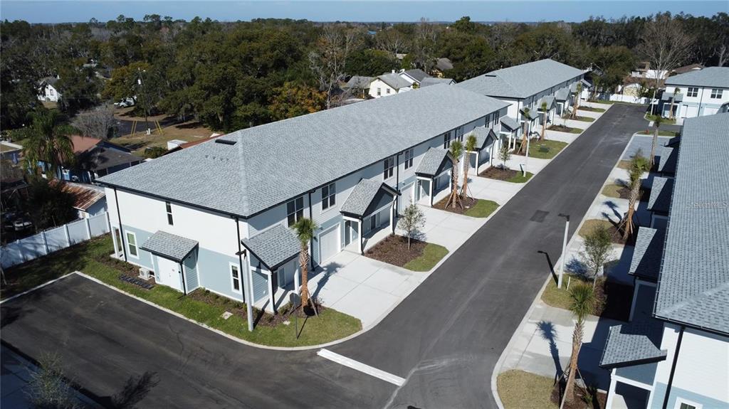 An aerial view shows a row of modern townhouses with gray roofs and paved driveways — 1111 E CAROLINE STREET, TAVARES, FL