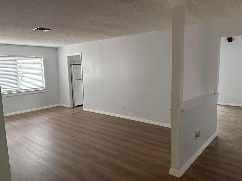 An empty room with light gray walls, wood-look flooring, and a partial wall divider — 2380 TIMBERCREST CIRCLE W, CLEARWATER, FL