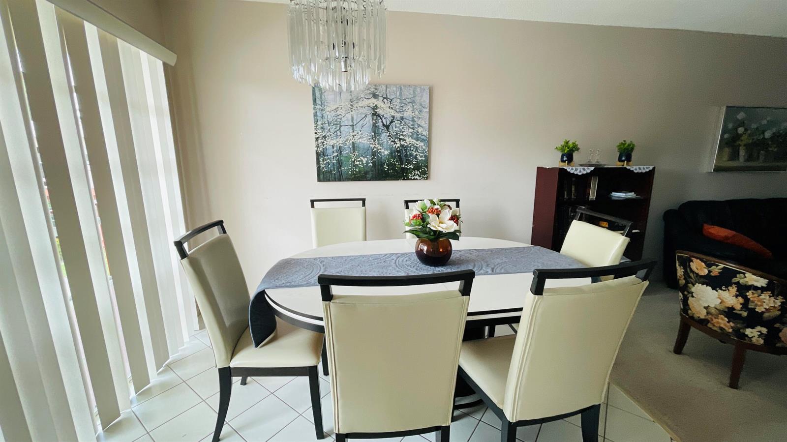 A dining room features a round table with four cream chairs and a crystal chandelier — 19 Golfs Edge, West Palm Beach FL 33417, WEST PALM BEACH, FL