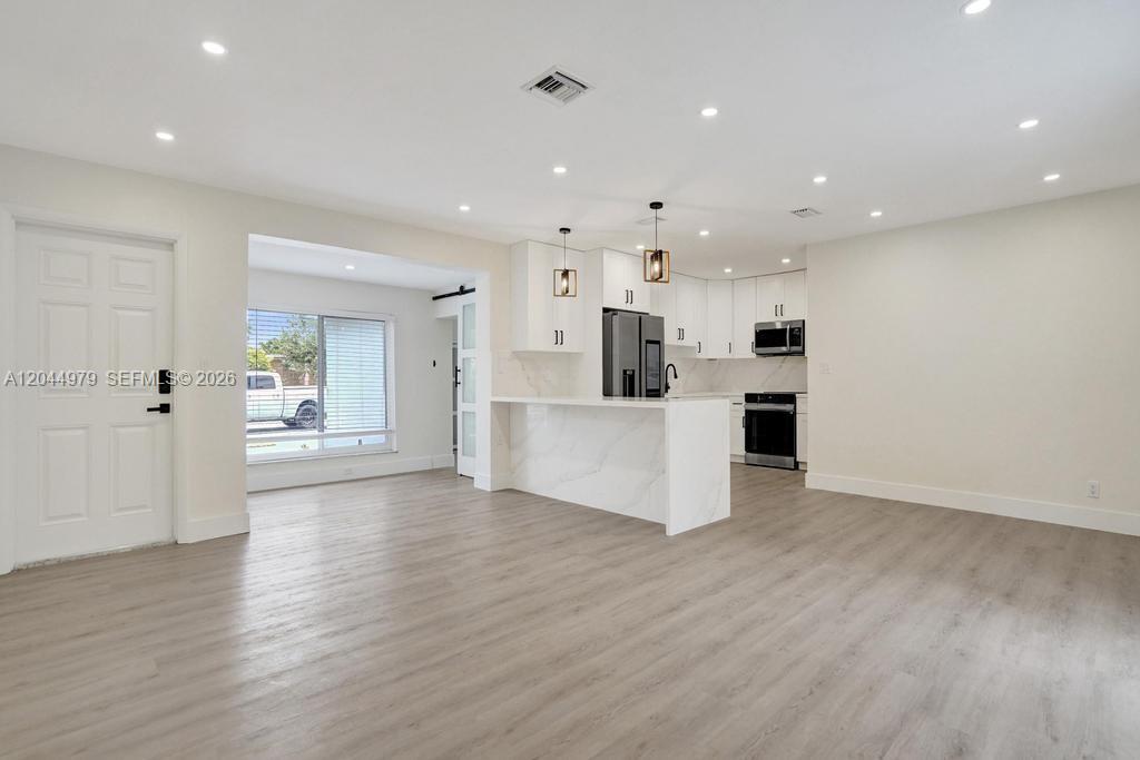An open-concept kitchen features white cabinetry, a marble-patterned island, and light wood-look flooring — 211 SW 64th Ave, Pembroke Pines FL 33023, PEMBROKE PINES, FL