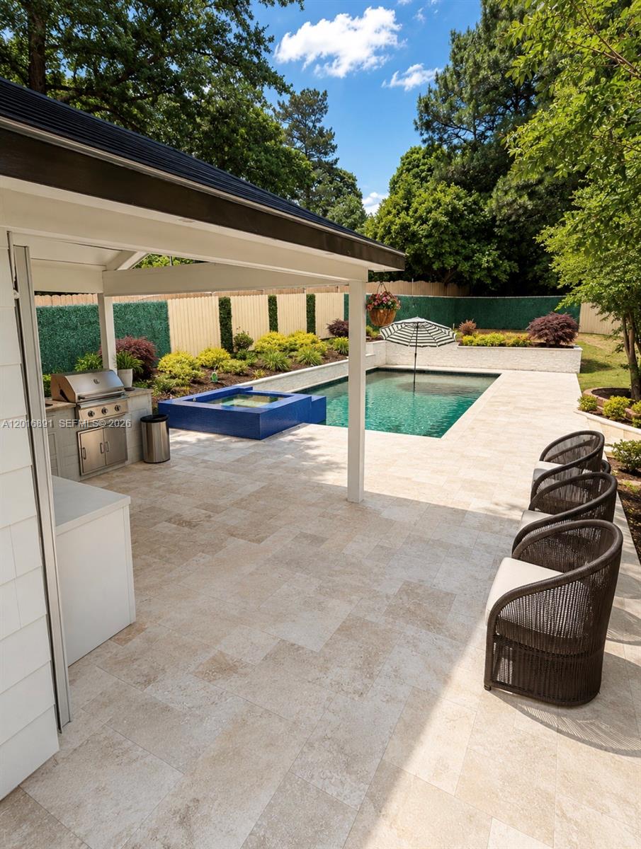 A covered outdoor kitchen overlooks a swimming pool with a blue tiled spa — 1393 Sutters Walk, GA 30045, GA