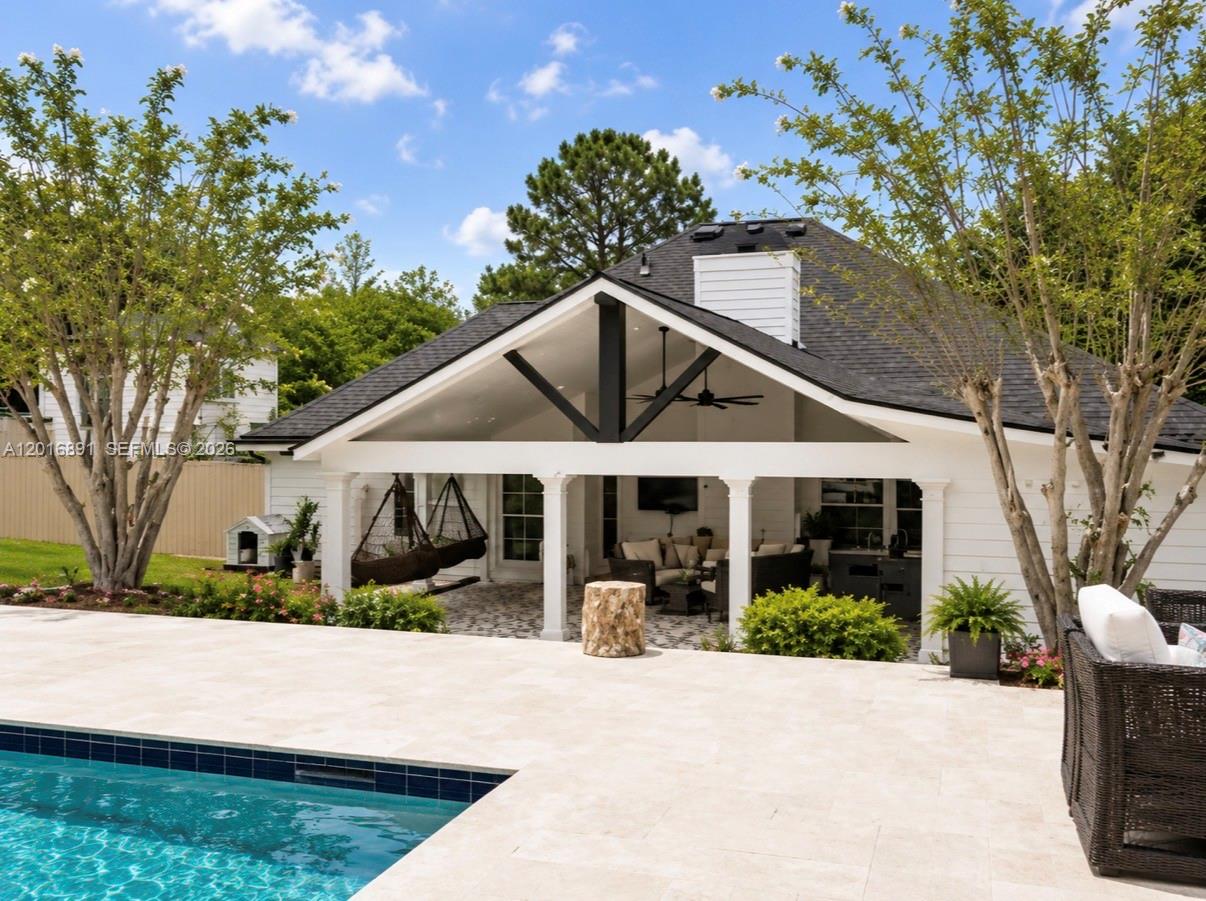 A covered patio with a gabled roof overlooks a swimming pool and stone deck — 1393 Sutters Walk, GA 30045, GA
