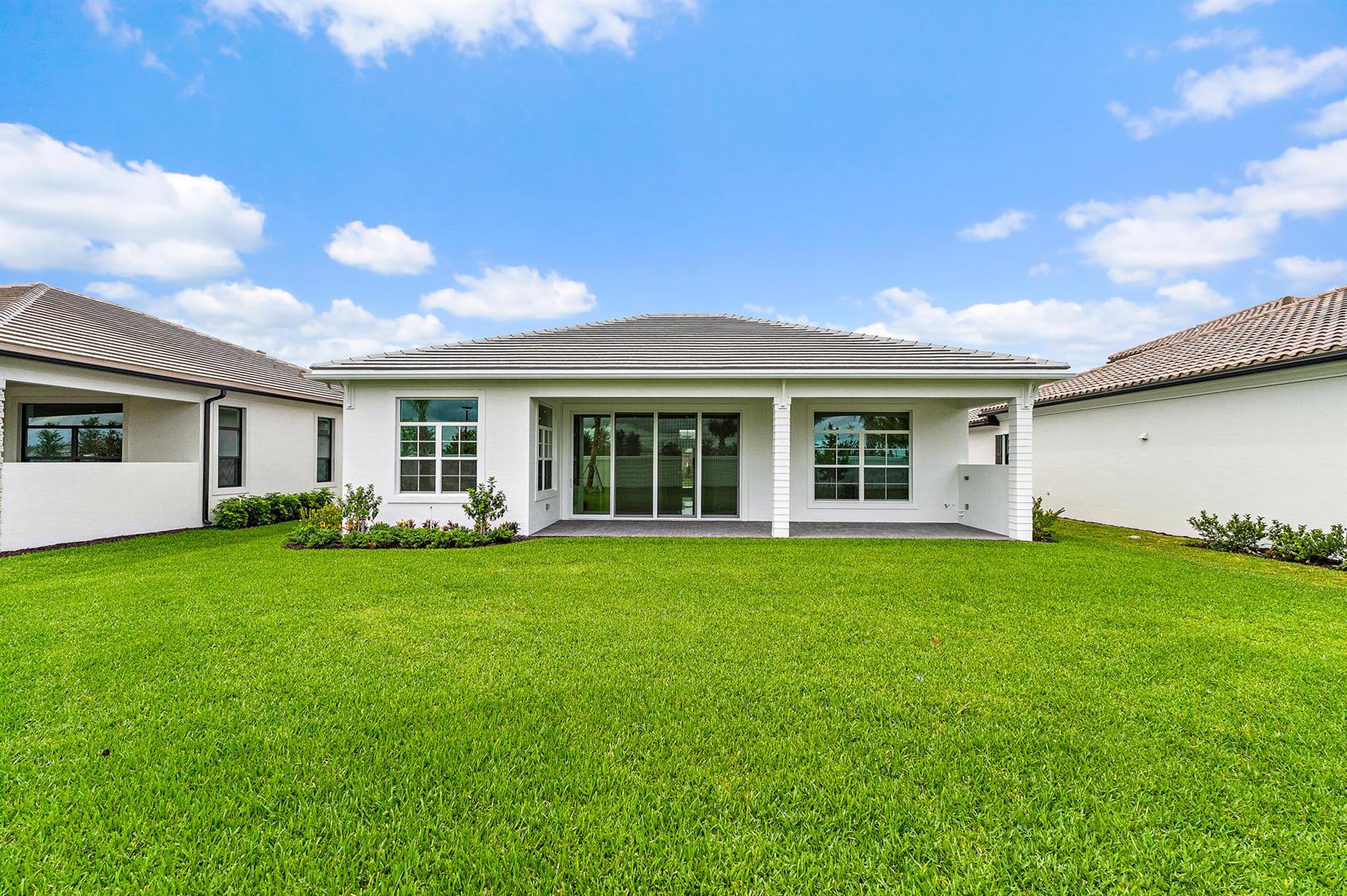 The exterior rear view of a white house with a covered patio and lawn — 9508 St. Germain, Palm Beach Gardens FL 33412, PALM BEACH GARDENS, FL
