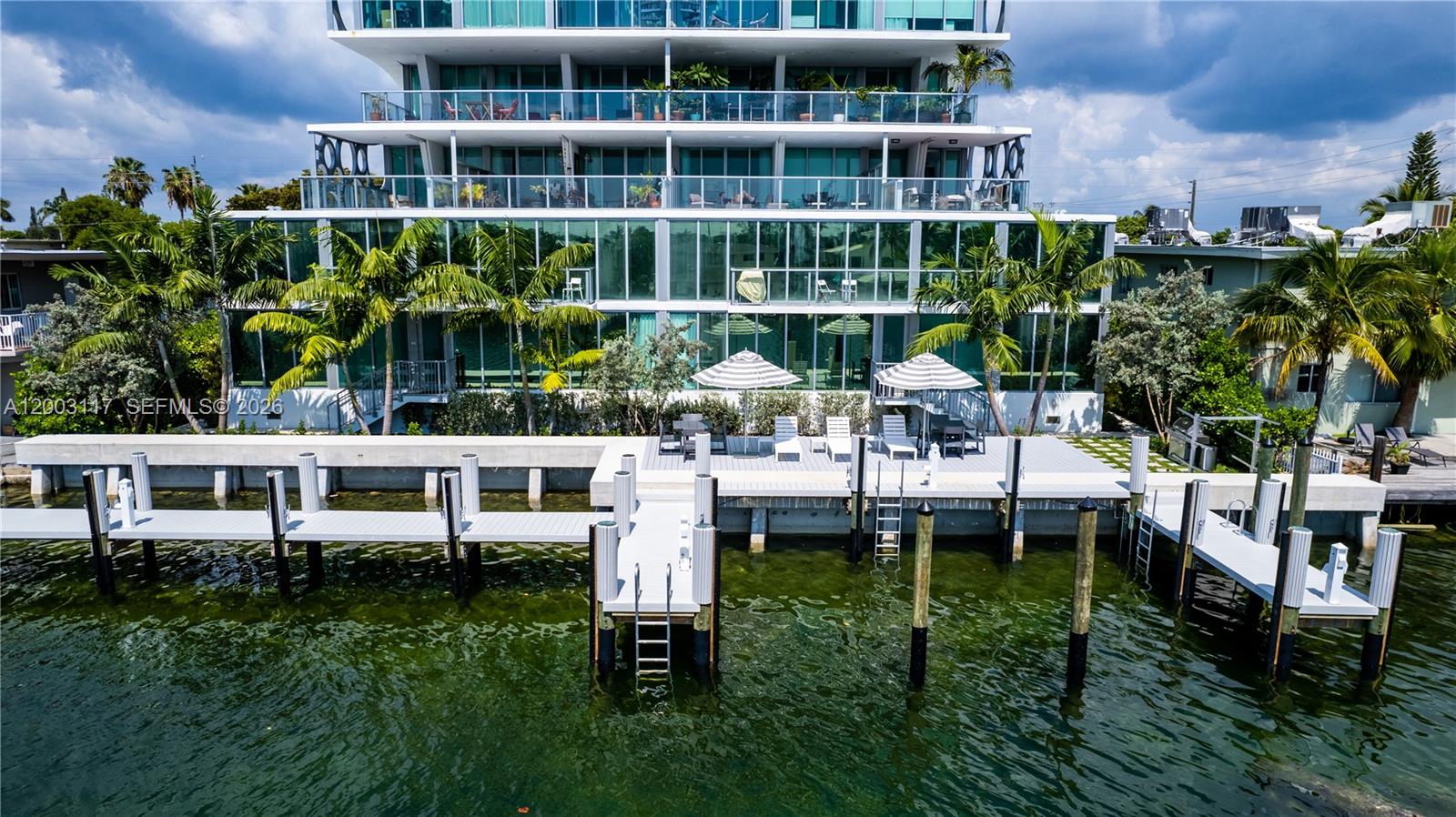 An exterior view of a modern multi-story building with glass balconies and a private dock — 8425 Crespi Blvd, Miami Beach FL 33141, MIAMI BEACH, FL