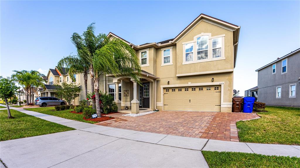 A two-story suburban house with a tan stucco exterior, a paved driveway, and palm trees — 2515 FONTAINE DRIVE, KISSIMMEE, FL
