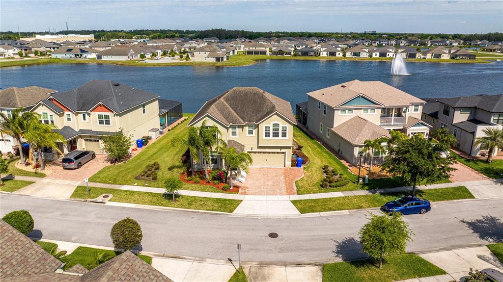 An aerial view shows three suburban houses situated along a lake with a fountain — 2515 FONTAINE DRIVE, KISSIMMEE, FL