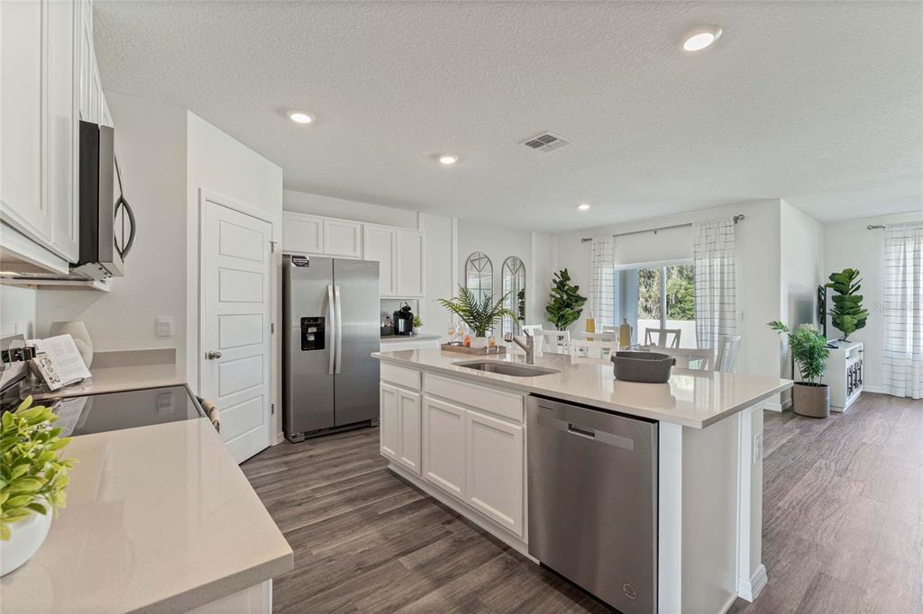 A modern kitchen features white cabinets, stainless steel appliances, and a large central island — 8595 CAPE FOX COVE, LAKELAND, FL