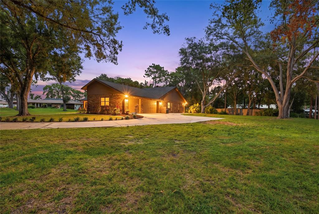 A single-story brick house with a multi-car garage sits on a large, grassy lot — 10616 FOREST RUN DRIVE, BRADENTON, FL