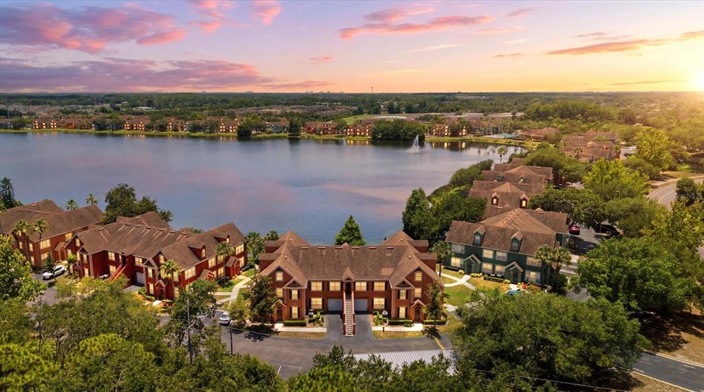 An aerial view of apartment buildings situated along a lake at sunset — 9256 LAKE CHASE ISLAND WAY, TAMPA, FL