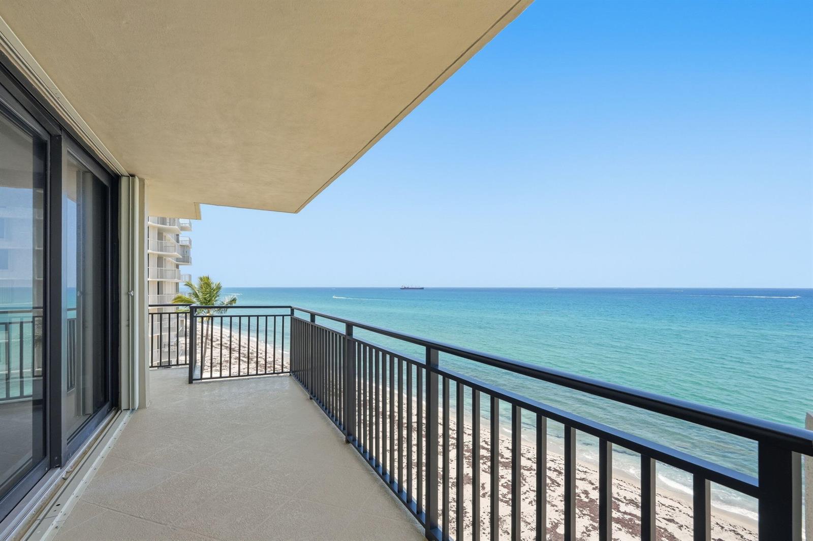 A balcony with a black metal railing overlooks a sandy beach and the ocean — 5460 N Ocean Drive # 6a, Riviera Beach FL 33404, RIVIERA BEACH, FL