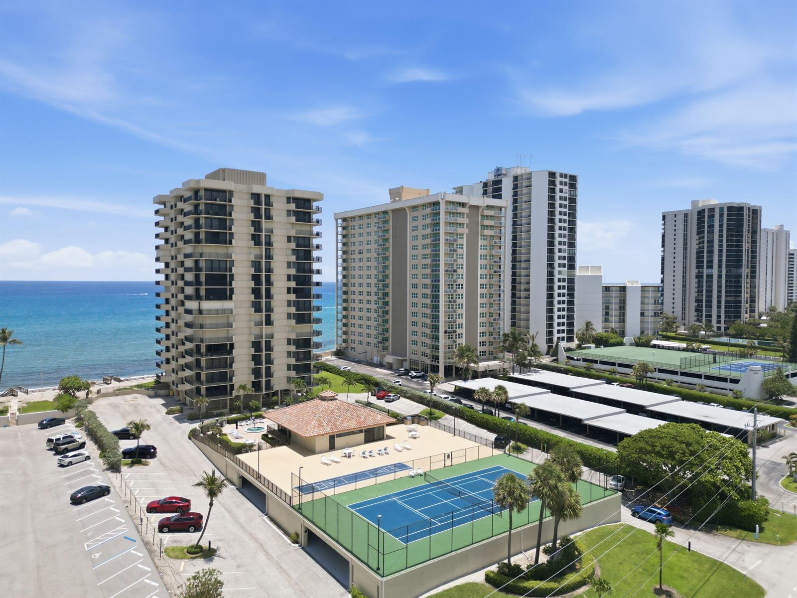 An aerial view shows high-rise apartment buildings, a tennis court, and a parking lot — 5460 N Ocean Drive # 6a, Riviera Beach FL 33404, RIVIERA BEACH, FL