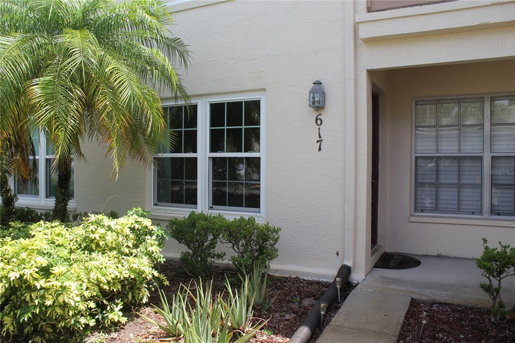 The exterior of a tan residential building features a front entrance and a palm tree — 7924 HARDWICK DRIVE UNIT 617, NEW PORT RICHEY, FL