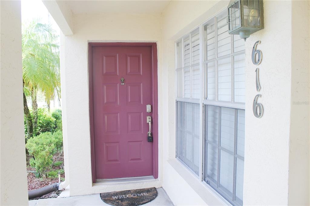 A front entrance features a red door, a welcome mat, and the house number 616 — 7924 HARDWICK DRIVE UNIT 617, NEW PORT RICHEY, FL
