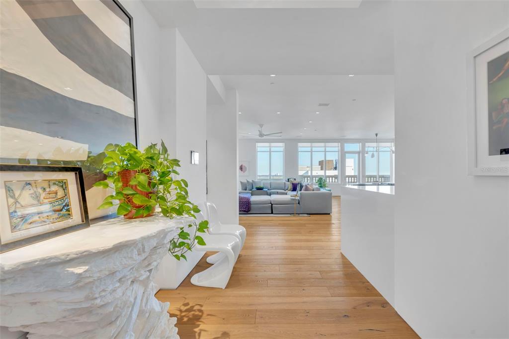 A bright entryway with a textured console table leads into a living room with hardwood floors — 100 S EOLA DRIVE UNIT PH 116, ORLANDO, FL