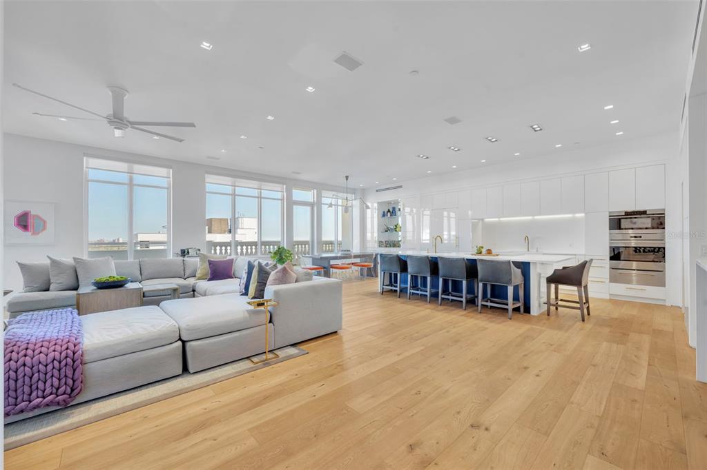 A modern open-concept living room and kitchen with light wood floors and white cabinetry — 100 S EOLA DRIVE UNIT PH 116, ORLANDO, FL