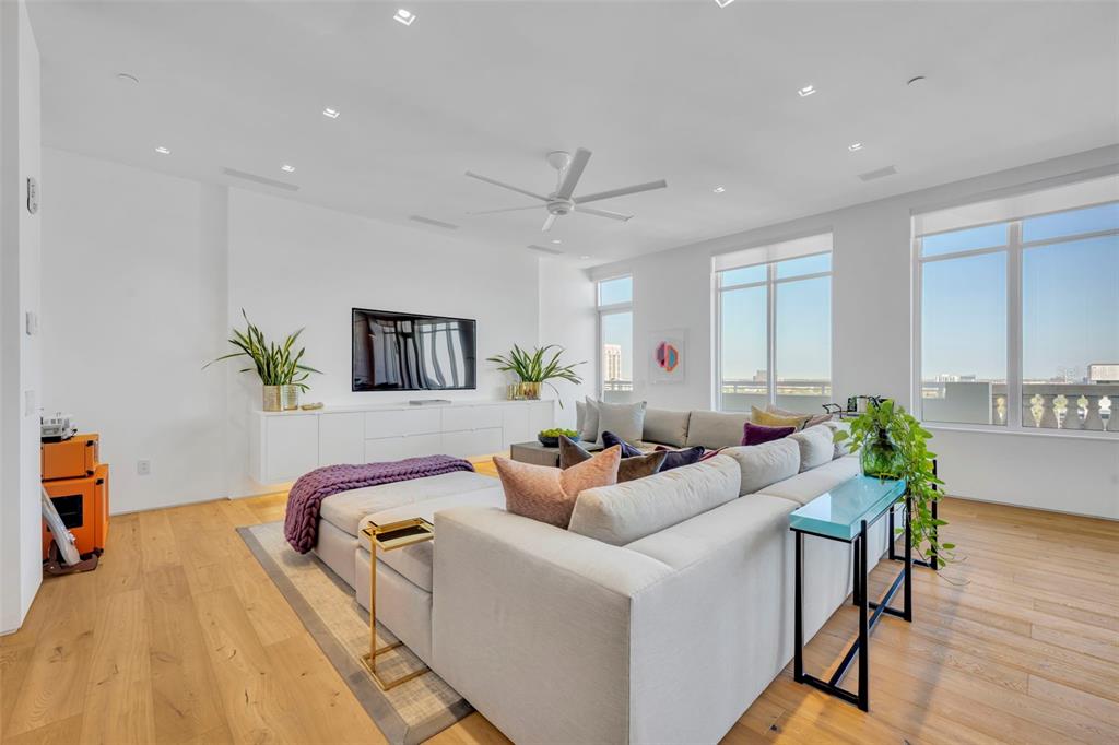 A modern living room features a large sectional sofa, a wall-mounted television, and floor-to-ceiling windows — 100 S EOLA DRIVE UNIT PH 116, ORLANDO, FL