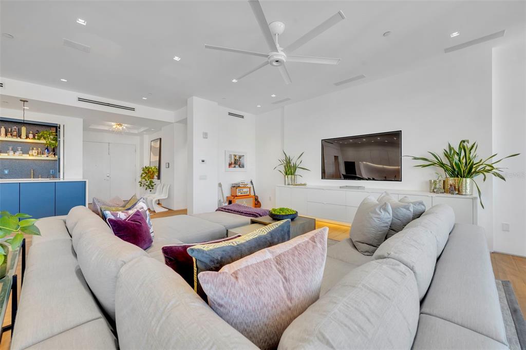 A modern living room features a large gray sectional sofa, a wall-mounted television, and a bar — 100 S EOLA DRIVE UNIT PH 116, ORLANDO, FL