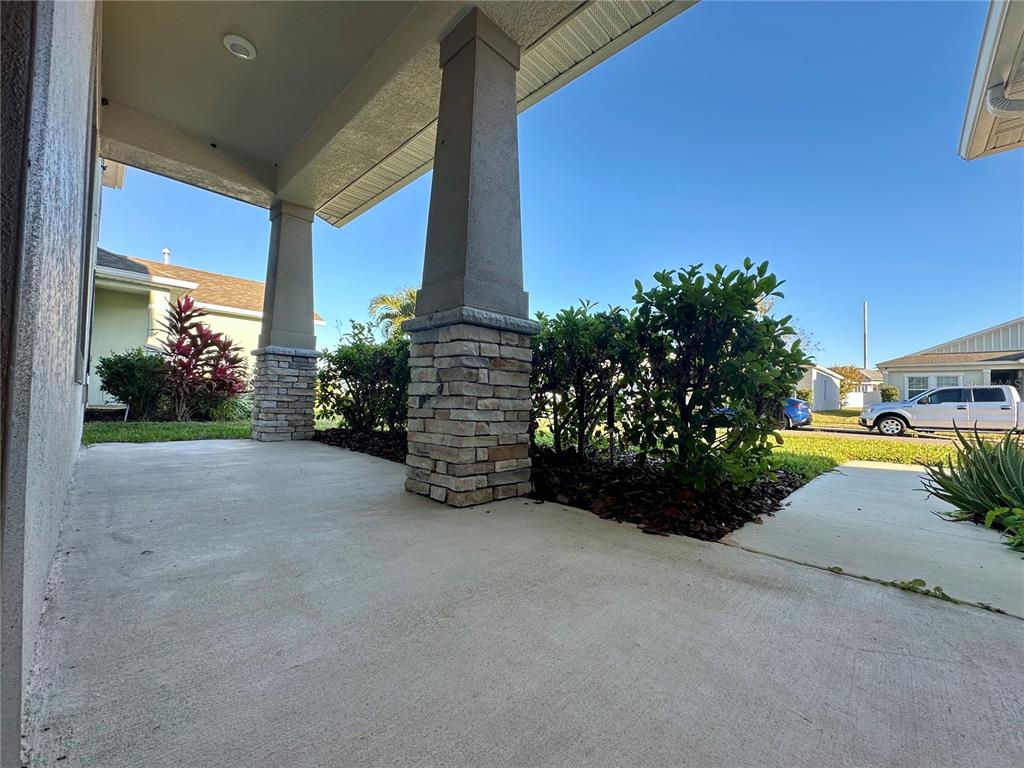 A covered front porch features two stone-based columns and a concrete floor — 177 BELLA VERANO WAY, DAVENPORT, FL