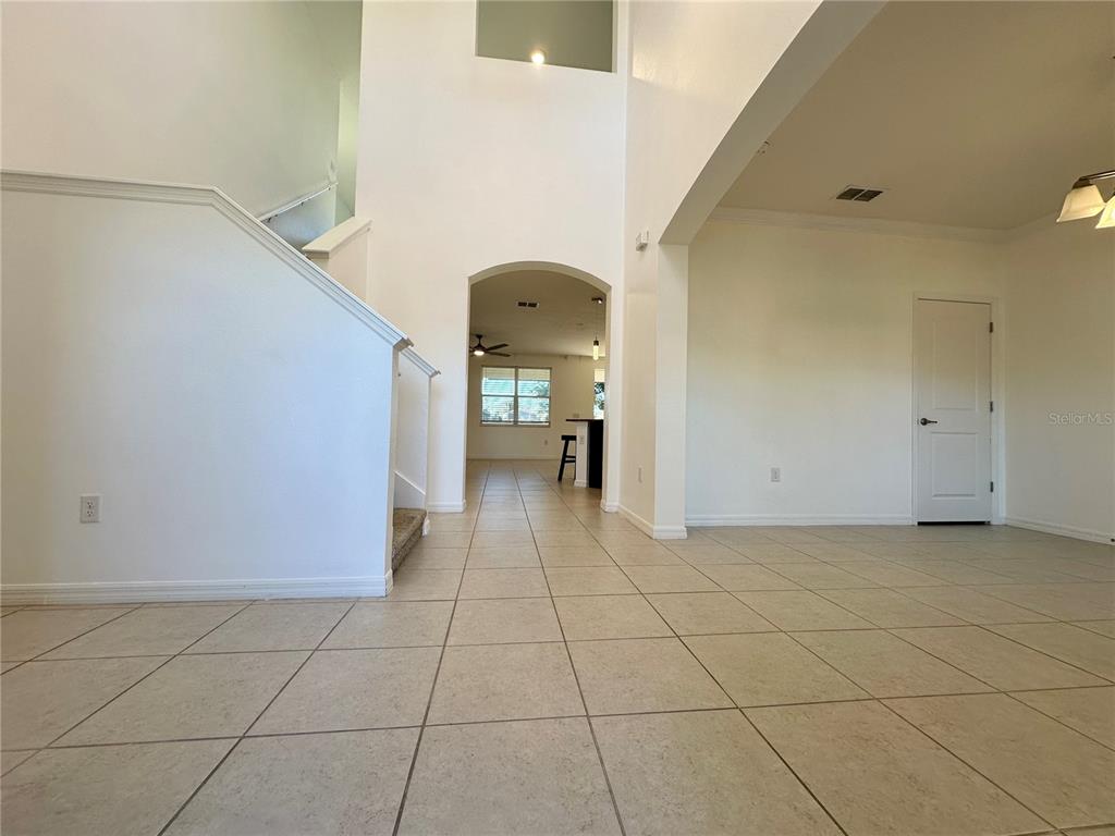 A tiled foyer leads to a staircase and an arched doorway opening into a kitchen — 177 BELLA VERANO WAY, DAVENPORT, FL