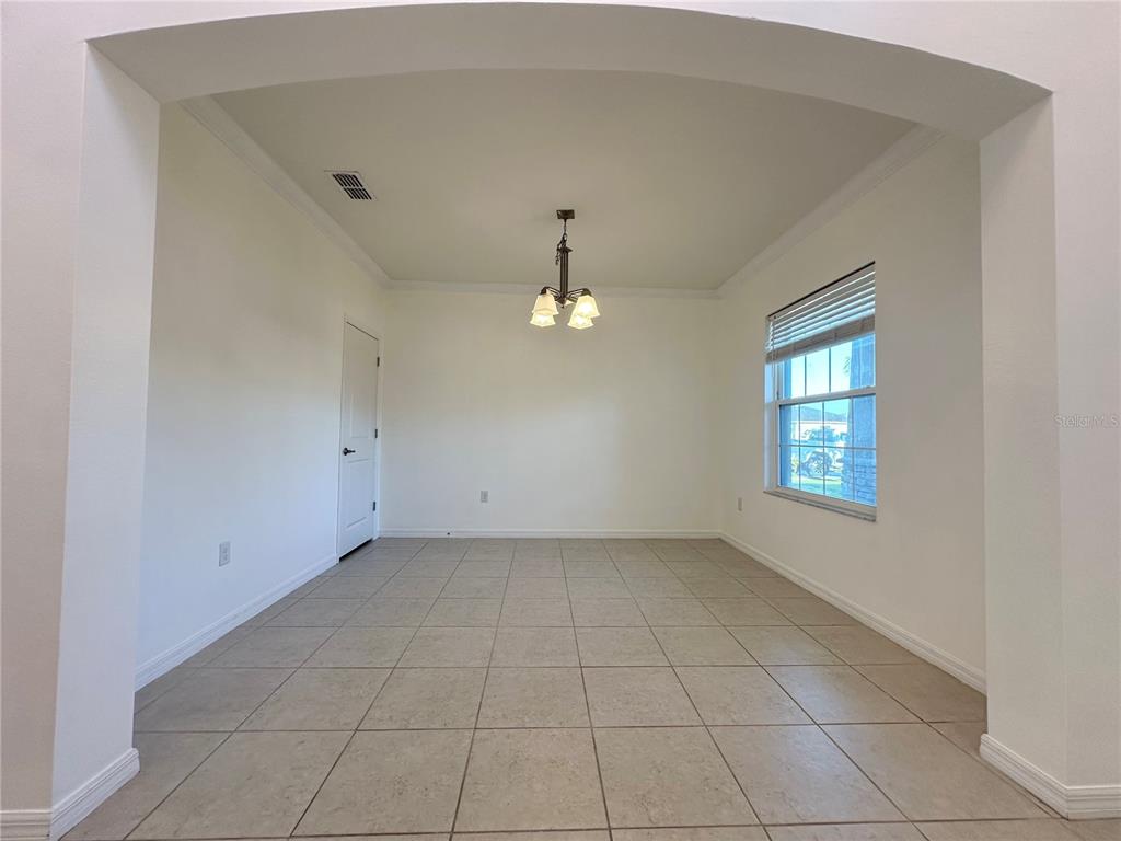An empty dining room features tile flooring, a chandelier, and an arched entryway — 177 BELLA VERANO WAY, DAVENPORT, FL