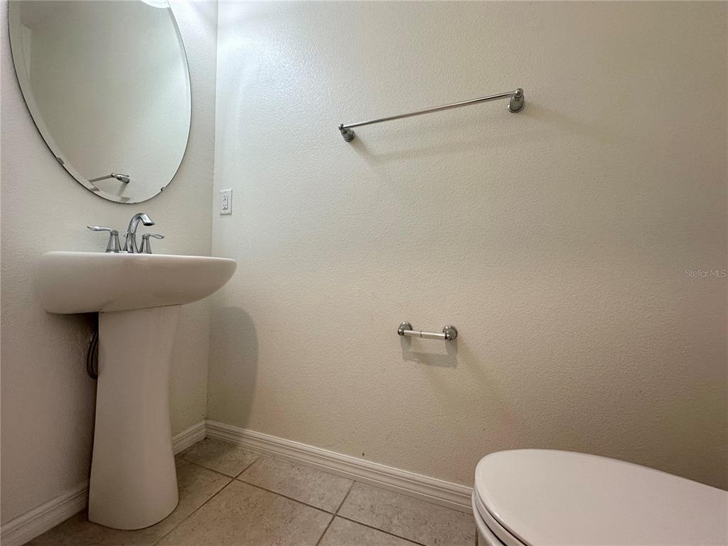 A small bathroom features a pedestal sink, an oval mirror, and a towel bar — 177 BELLA VERANO WAY, DAVENPORT, FL