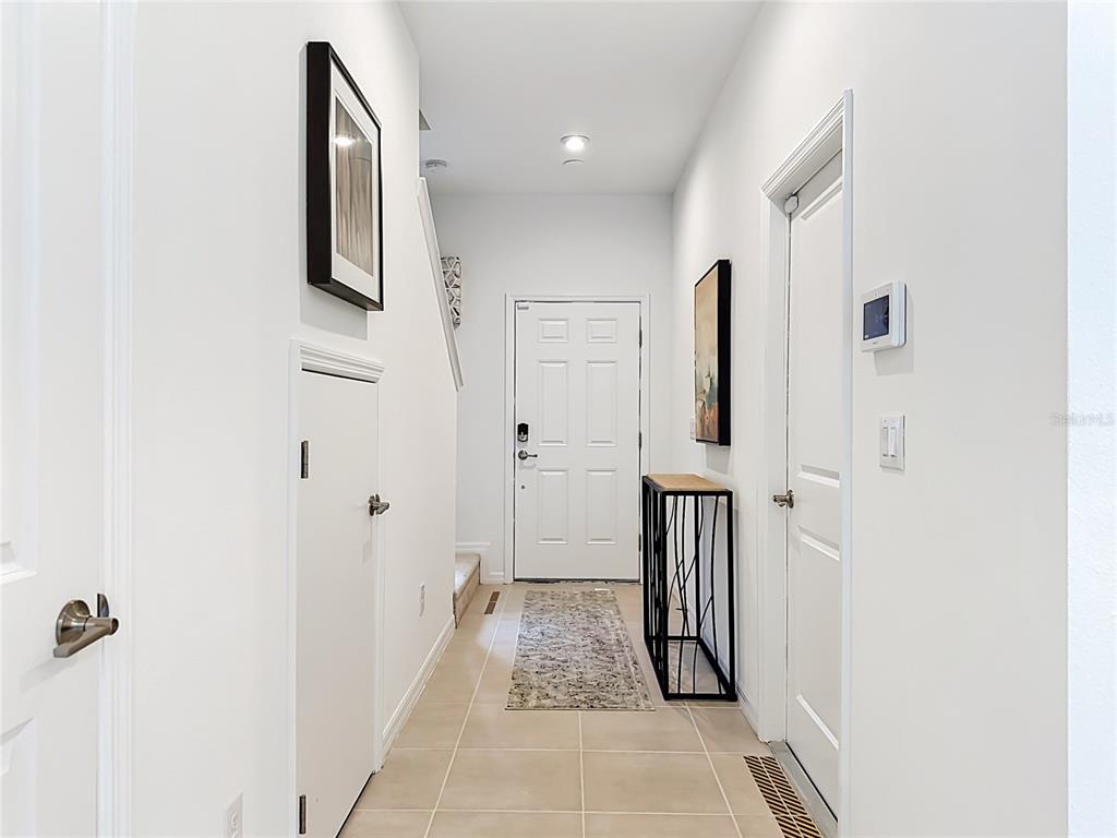 A bright entryway features tile flooring, white walls, a front door, and a small console table — 8429 LUNAR SKYE ST, SARASOTA, FL
