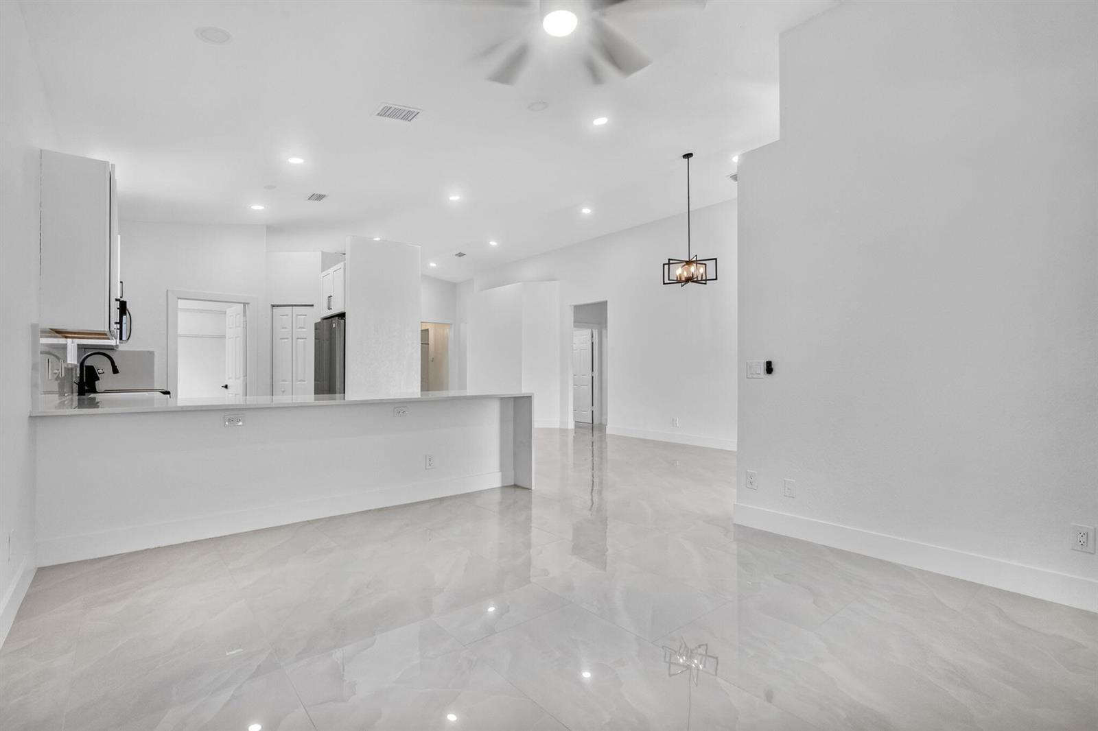 A bright, open-concept kitchen and living area featuring white cabinetry, quartz countertops, and tile flooring — 13844 SW 53rd Street, Miramar FL 33027, MIRAMAR, FL