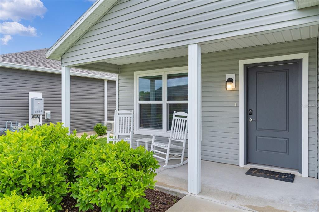 A front porch with two white rocking chairs and a gray door on a house — 1926 HUX COURT, THE VILLAGES, FL