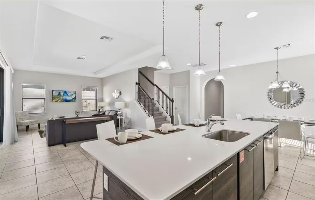 A modern kitchen with a large white island overlooks an open-concept living and dining area — 167 CLAFFEY COURT, HAINES CITY, FL