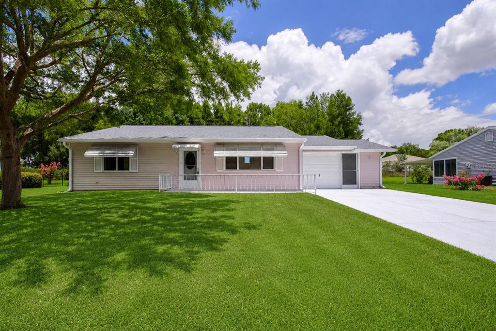 A single-story pink house with a white metal railing, a garage, and a large lawn — 9021 SW 108TH PLACE, OCALA, FL