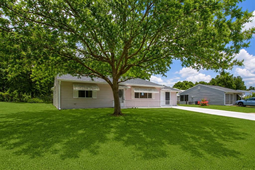 A single-story house with light siding and a large tree in the front yard — 9021 SW 108TH PLACE, OCALA, FL