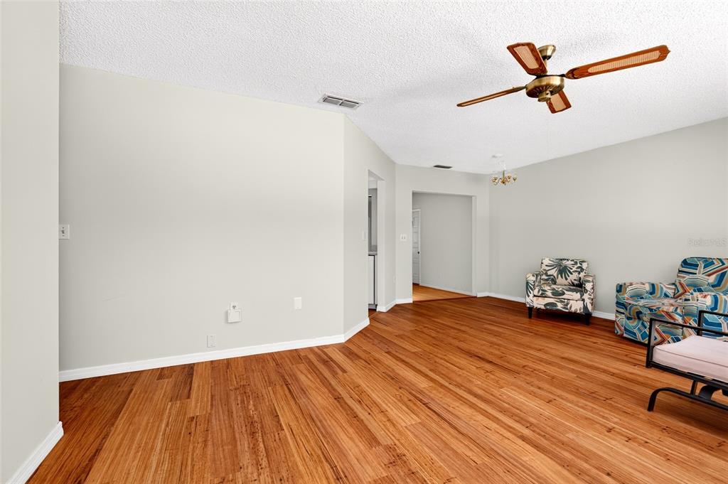 A living room features light-colored walls, wood-look flooring, a ceiling fan, and patterned armchairs — 9021 SW 108TH PLACE, OCALA, FL
