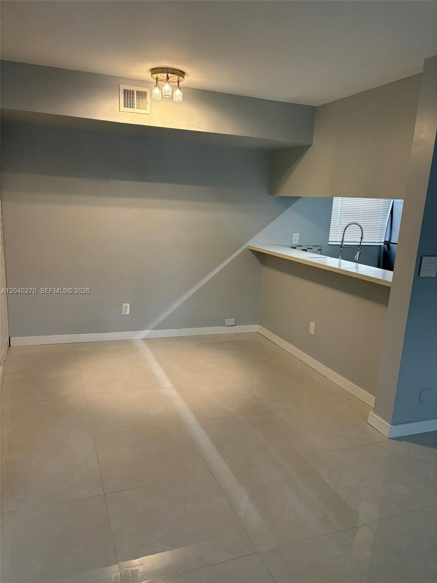 This dining area features light gray walls, tile flooring, and a breakfast bar — 18350 Mediterranean Blvd # 27, Hialeah FL 33015, HIALEAH, FL