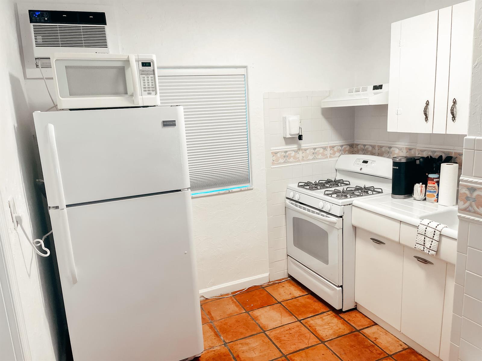 A kitchen features a white refrigerator, gas stove, and terracotta tile flooring — 516 3rd Avenue S, FL 33460, FL