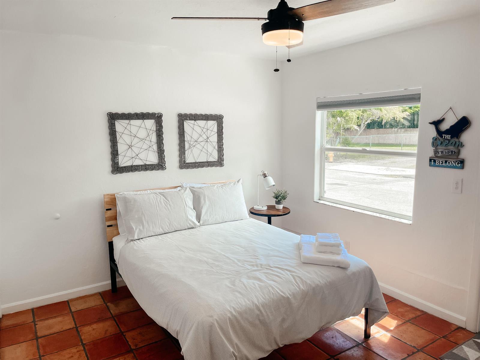 A bedroom with a bed, two wall decorations, a ceiling fan, and terracotta tile flooring — 516 3rd Avenue S, FL 33460, FL