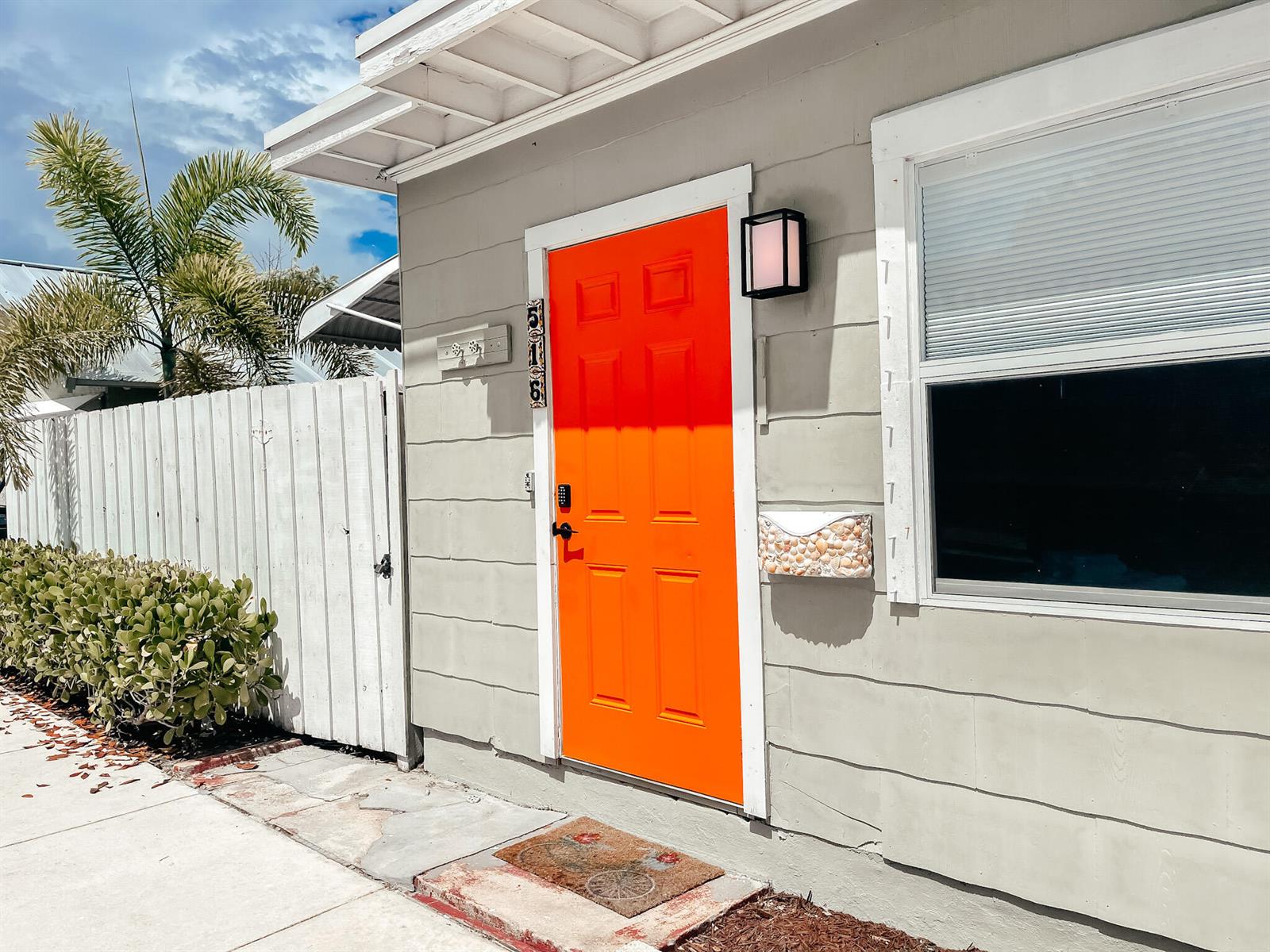 A bright orange front door stands on the exterior of a light gray house — 516 3rd Avenue S, FL 33460, FL