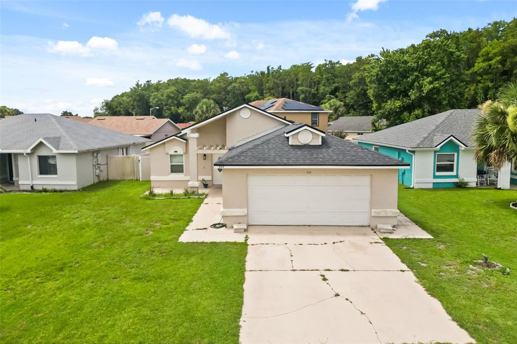 A tan single-story house with a two-car garage and a dark shingled roof — 948 OCALA WOODS LANE, ORLANDO, FL