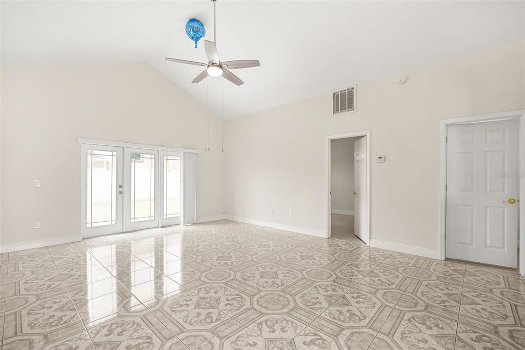 A bright, empty room features vaulted ceilings, a ceiling fan, and patterned tile flooring — 948 OCALA WOODS LANE, ORLANDO, FL