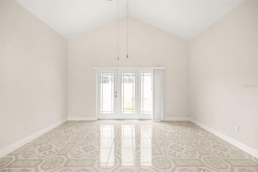 A bright room with vaulted ceilings, tiled floors, and glass doors leading to the outdoors — 948 OCALA WOODS LANE, ORLANDO, FL